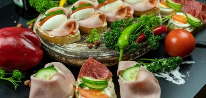 Delicious open-faced sandwiches with ham, eggs, and veggies on a wooden platter.