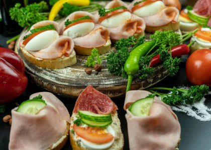 Delicious open-faced sandwiches with ham, eggs, and veggies on a wooden platter.