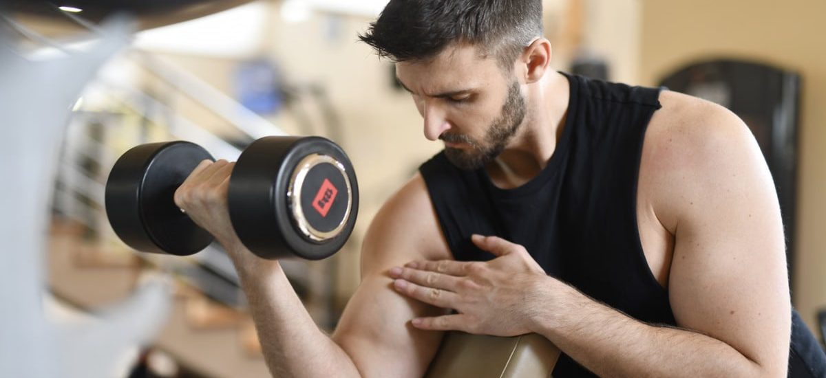Focused man lifting dumbbell, showcasing strength and fitness indoors.