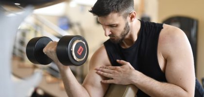Focused man lifting dumbbell, showcasing strength and fitness indoors.