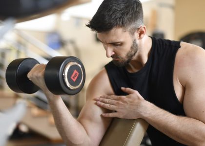 Focused man lifting dumbbell, showcasing strength and fitness indoors.